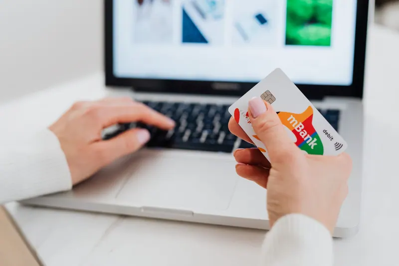 Person bezahlt online am Laptop mit einer Karte